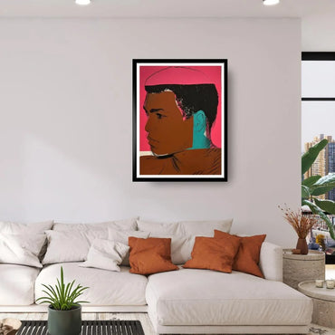 Framed artwork of a stylized portrait on a wall above a sofa with decorative pillows.