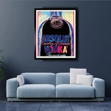 Framed Absolut Vodka poster on a dark wall above a light blue sofa.