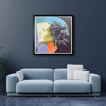 Modern living room with a light blue sofa and a framed abstract portrait artwork on the wall.