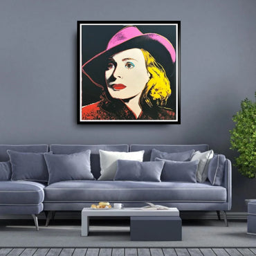 Framed artwork of a woman with a pink hat on a gray wall above a gray sofa.