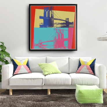 White sofa with colorful pillows in a living room with a framed artwork of the Brooklyn Bridge on the wall.