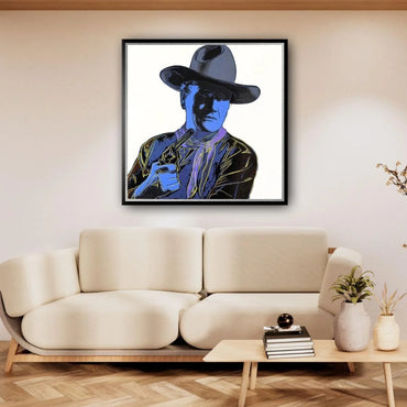 Framed artwork of a person in a cowboy hat on a wall above a beige sofa.