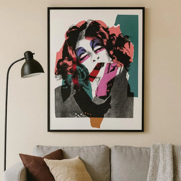 Abstract portrait painting above a beige couch with brown and beige pillows and a black lamp. Decor Inspiration 2025.