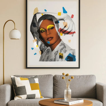 Framed artwork of a trans woman with colorful abstract elements above a gray sofa with decorative pillows.