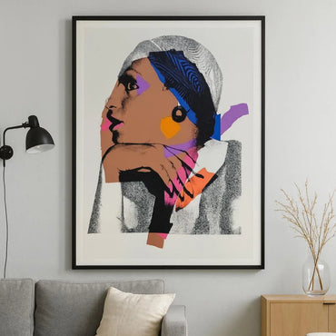 Framed abstract art of a woman's face on a wall above a sofa.