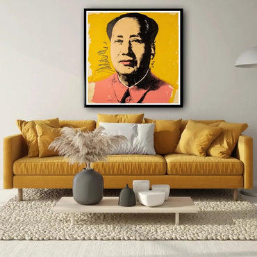 Yellow sofa with decorative pillows in a living room setting, featuring a framed portrait above.