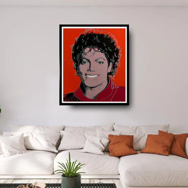 Framed portrait of a famous person on a wall above a white sofa with orange cushions.