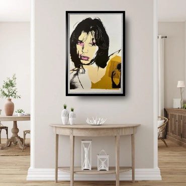 Framed abstract portrait on a wall above a wooden console table.