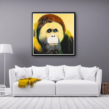 Framed artwork of an orangutan on a gray wall above a white sofa with a yellow blanket.