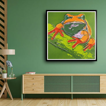Framed artwork of a colorful frog on a green wall above a wooden cabinet.