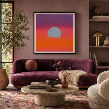 Living room with a purple sofa, round coffee table, and abstract sunset painting on the wall.