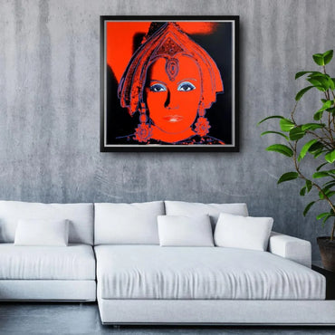 Framed artwork of a stylized face with red and black colors on a gray wall above a white sofa.