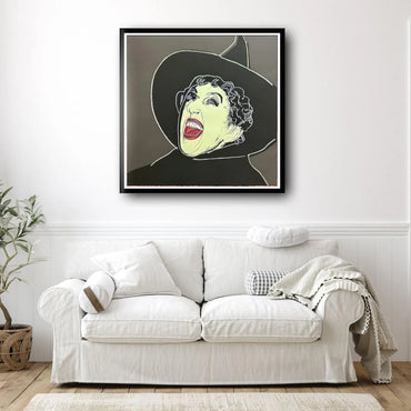 Framed artwork of a stylized Wicked Witch on a wall above a white sofa.