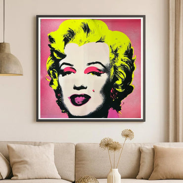 Framed artwork of a famous Andy Warhol pop art portrait Marilyn #31 with diamond dust background with bright colors on a pink background in living room.