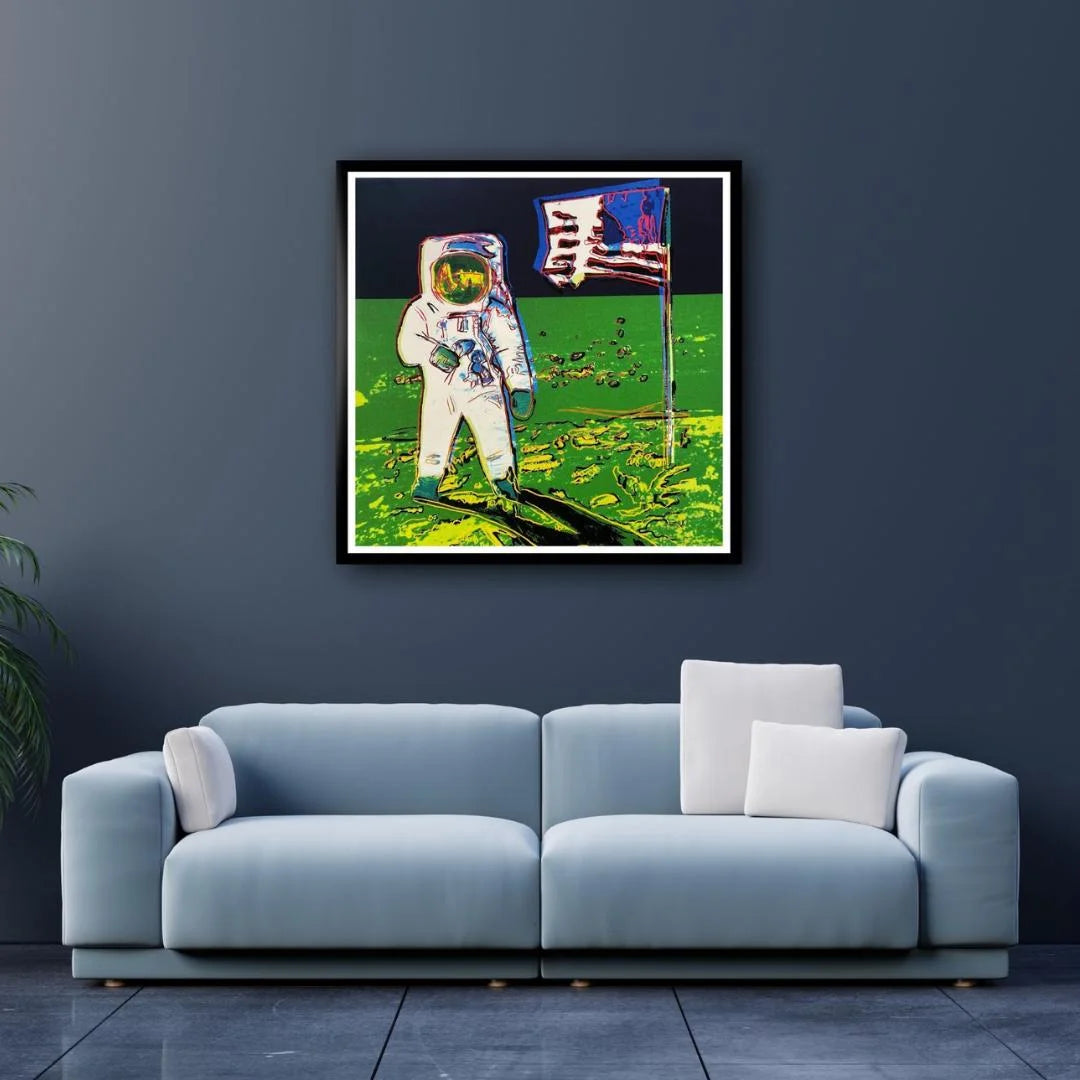 Framed artwork of an astronaut on the moon above a blue sofa. Luxury home decor ideas. Andy Warhol Moonwalk.