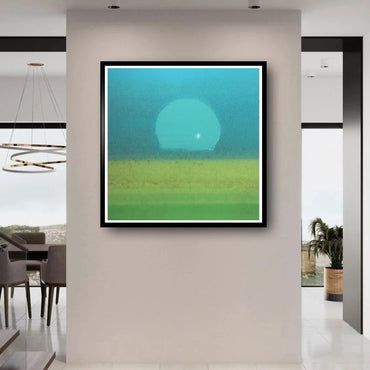 Framed abstract artwork with a blue and green gradient sunset on a wall in a modern interior setting.