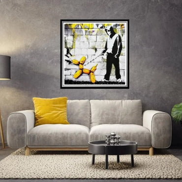 Living room with a gray sofa, yellow pillow, and framed artwork on the wall.
