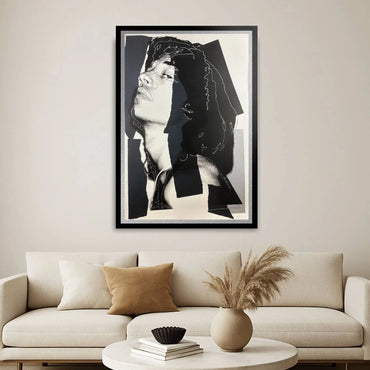 Framed black and white art print above a beige sofa in a living room.