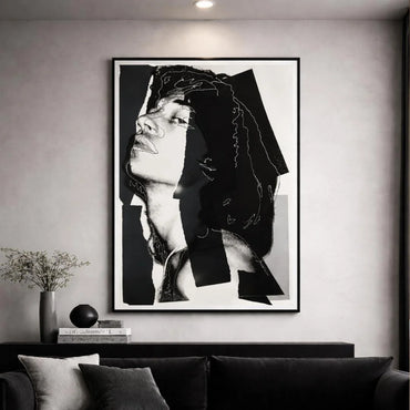 Framed black and white art print of a woman's face on a wall above a sofa.