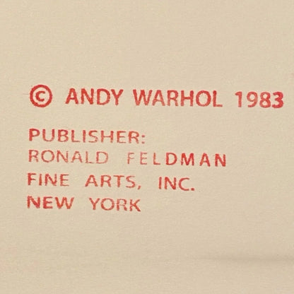 Red text crediting Andy Warhol and Ronald Feldman Fine Arts, Inc. on a beige background