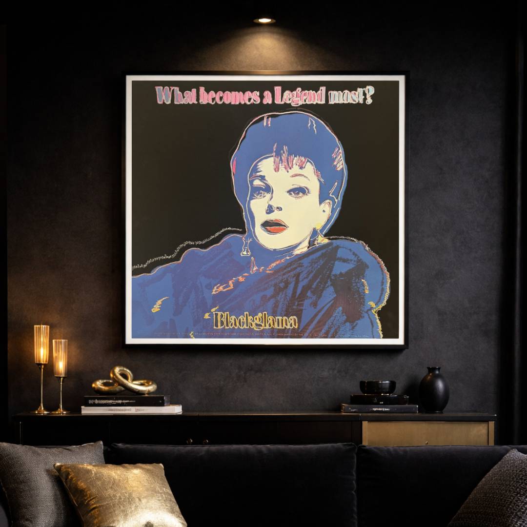 Framed artwork of a stylized portrait with text on a dark wall above a sofa.