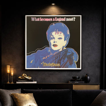 Framed artwork of a stylized portrait with text on a dark wall above a sofa.