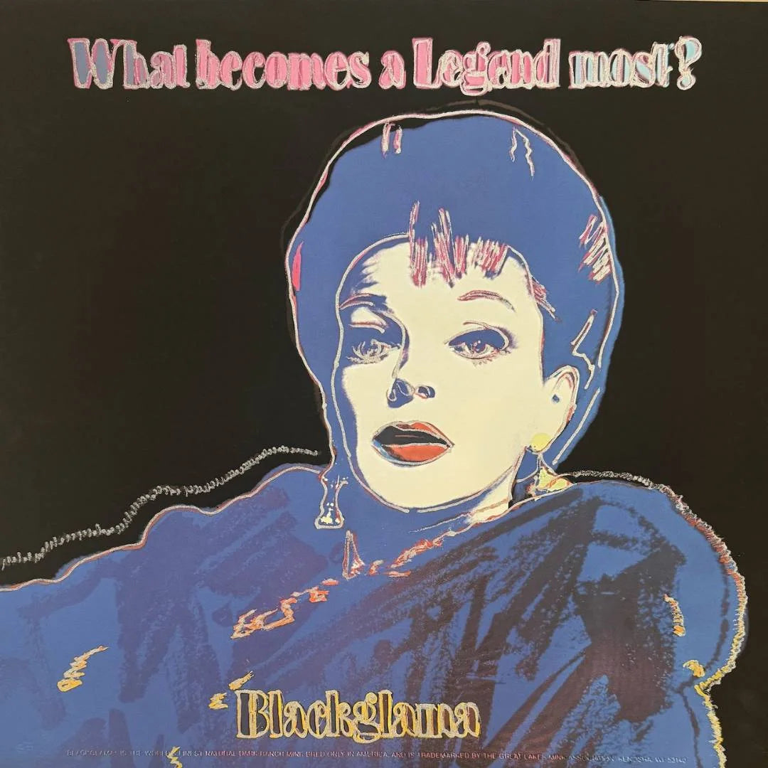 Artistic depiction of a person with a blue headscarf and red lipstick, with text 'What becomes a legend now?' and 'Blackglama' on a dark background.