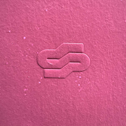Textured pink surface with a logo or symbol embossed in the center.