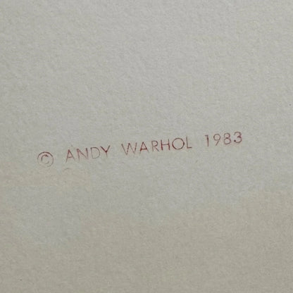 Signature and year '1983' by Andy Warhol on a textured beige background