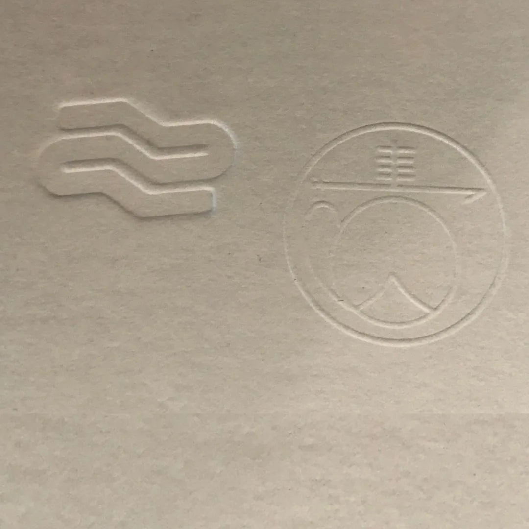 Two embossed symbols on a textured beige surface