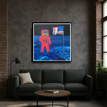 Framed artwork of an astronaut and American flag on a gray wall above a dark sofa.