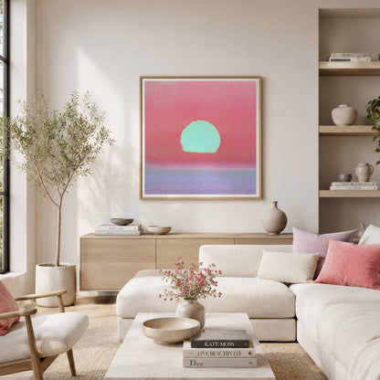A framed abstract wall art print hangs above a light wood console in a bright, modern living room. The artwork features a pink and coral sky with a mint green sun and a lavender-purple horizon.