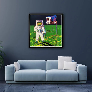 Framed artwork of an astronaut on the moon above a blue sofa. Luxury home decor ideas. Andy Warhol Moonwalk.