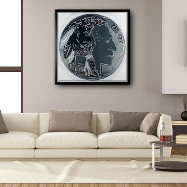 Framed artwork of a coin with a profile design on a wall above a beige sofa.
