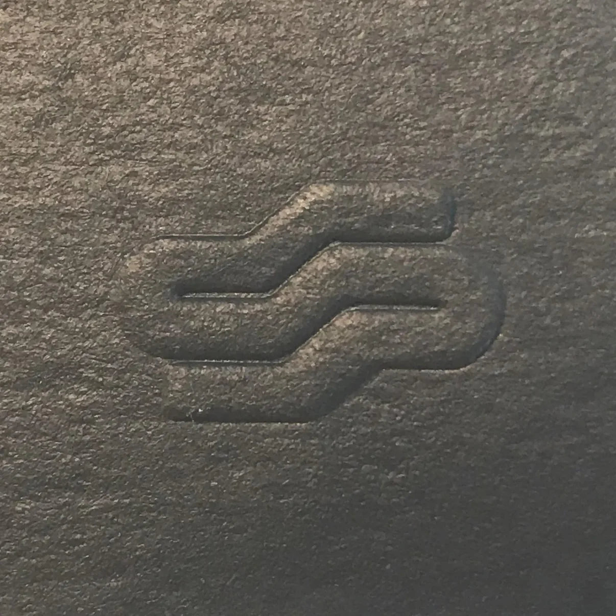 Close-up of a textured dark surface with a subtle logo or design.