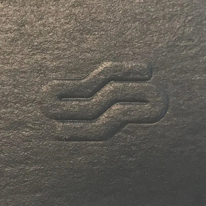 Close-up of a textured dark surface with a subtle logo or design.