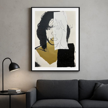 Framed abstract art of a face on a gray wall above a dark gray sofa.