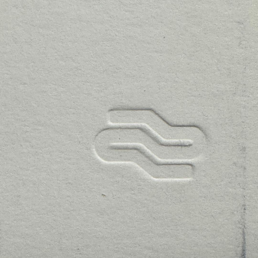 Close-up of a textured gray surface with a subtle logo or symbol.